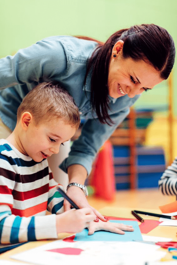 teacher helping student trace hand.